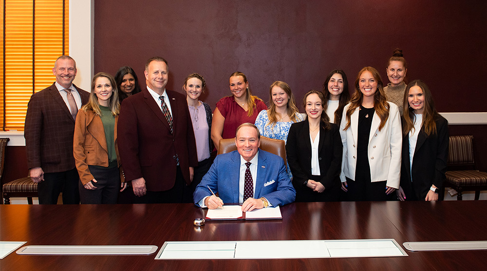 MSU President Mark E. Keenum signs a proclamation regarding National Nutrition Month at MSU, while students and faculty look on.